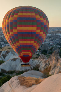 Hot air balloons flying over rock formation against sky