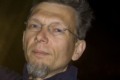 Close-up portrait of man wearing eyeglasses at night