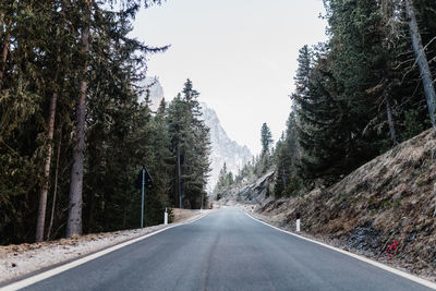 Empty road amidst trees against clear sky