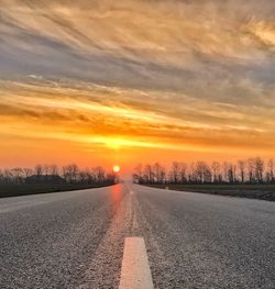 Snow covered road against sky during sunset