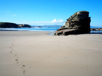 Rock formation at beach against clear blue sky