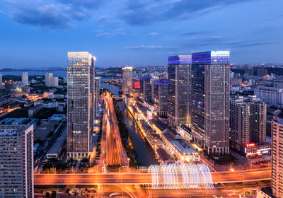Aerial view of city lit up against cloudy sky