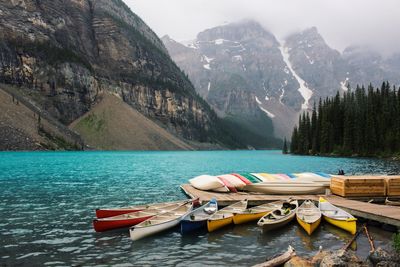 Boats at lakeshore by mountain during winter