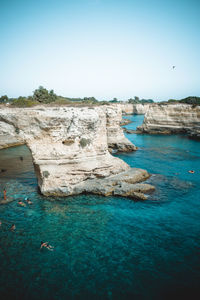 Rock formations in sea against clear blue sky