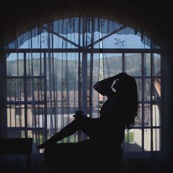 Side view of silhouette woman looking through window