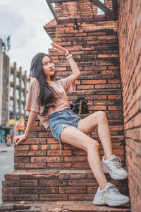 Young woman smiling while standing against brick wall