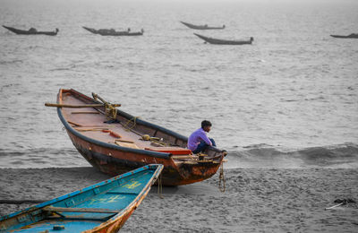 Rear view of man on boat moored at sea