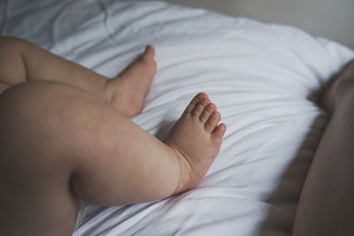 Low section of baby lying down on bed