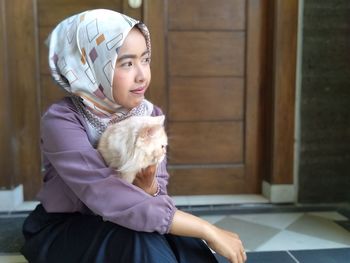 Woman in hijab with cat sitting at home