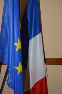 Close-up of flags hanging against blue wall