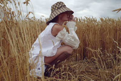 Full length of woman crouching at farm