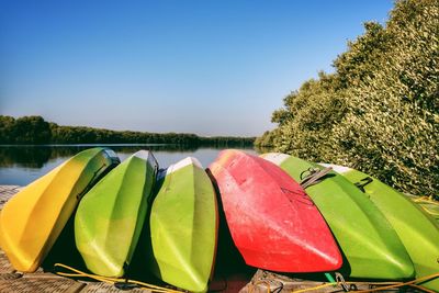 Close-up of multi colored kayaks on wooden bridge against clear blue sky