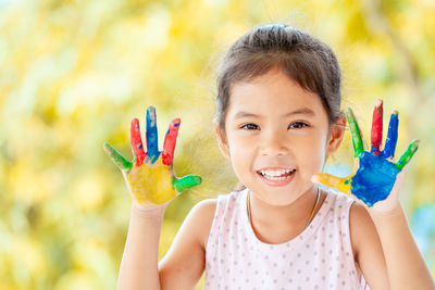 Close-up portrait of smiling girl with painted hands