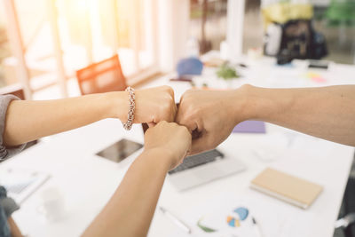 Colleagues giving fist bumps in office