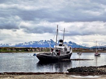 Boats in sea against cloudy sky