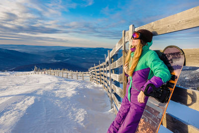 Person standing on snowcapped mountain against sky