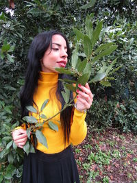 Young woman wearing hat standing against plants