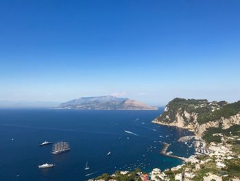 High angle view of sea and mountains against clear blue sky