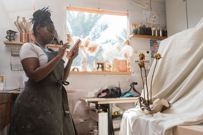 Female pottery artist business owner taking photos of her ceramics