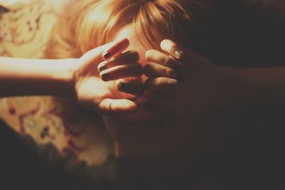 Close-up of woman covering eyes with hands