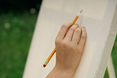 Cropped image of hand holding paper against blurred background