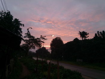 Silhouette trees on landscape against dramatic sky