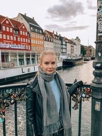 Portrait of smiling woman standing on bridge over river in city