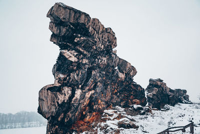 Rock formation on snow covered land against sky