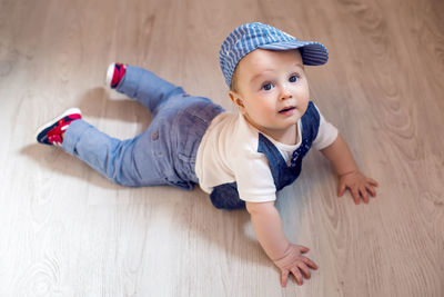 Gay boy kid blonde in a cap and pants lying on the floor