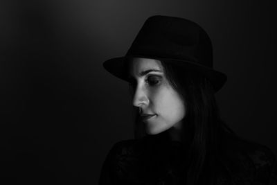 Close-up portrait of young woman against black background