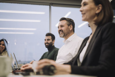 Smiling businesswoman with male and female colleagues discussing while working at office