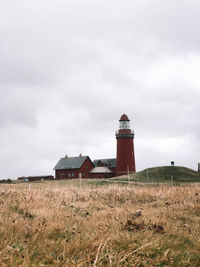 Lighthouse on field against sky