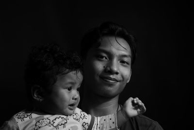 Portrait of mother and daughter against black background
