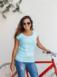 Young women with bicycle stays near a wall and smile