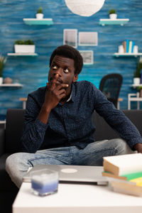 Young man looking down while sitting on table