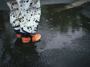 Low section of child standing in puddle