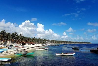 Boats moored at beach against blue sky