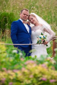 Portrait of wedding couple standing at field