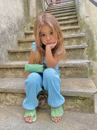 Portrait of cute girl sitting on staircase