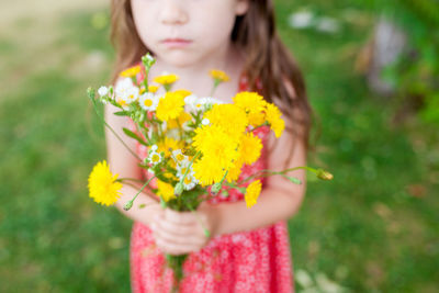 Midsection of girl holding flowers