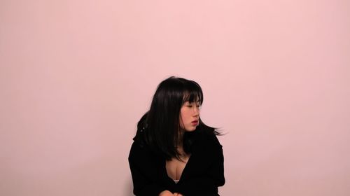 Sad young woman against pink background