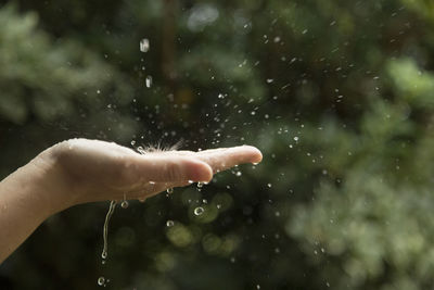 Cropped hand of woman holding water during rainy season