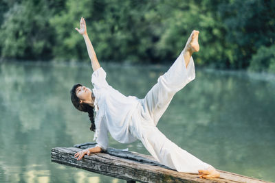 Yoga by the lake. young woman doing yoga exercise plank star pose