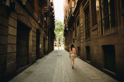 Woman walking on footpath amidst buildings in city