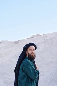 Portrait of bearded young man standing at desert