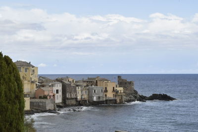 Buildings by sea against sky