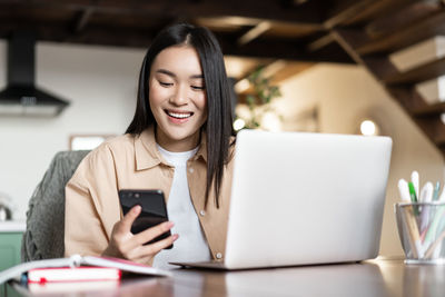 Portrait of young woman using laptop while sitting on table