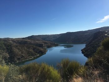 Scenic view of lake and mountains against clear blue sky