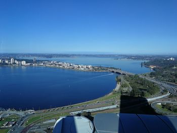 Aerial view of sea and cityscape against blue sky