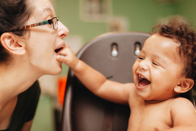 Laughing mother playing with son at home